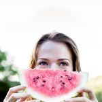 Pretty happy cute woman eating slice of juicy red watermelon out